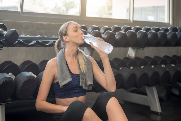 Foto joven atlética agua potable en un gimnasio.