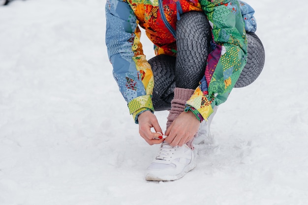 Una joven atlética ata sus zapatos en un día helado y nevado. Fitness, correr