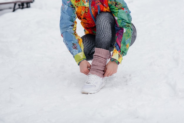 Una joven atlética ata sus zapatos en un día helado y nevado. Fitness, correr