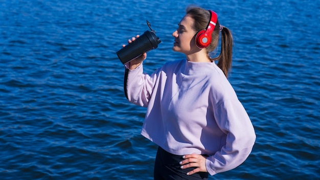 Una joven atlética bebe agua después de hacer ejercicio al aire libre