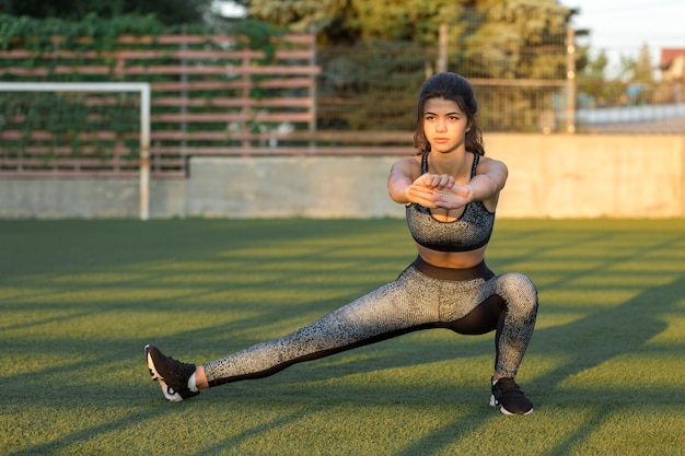 Una joven atlética delgada en ropa deportiva con estampados de piel de serpiente realiza una serie de ejercicios