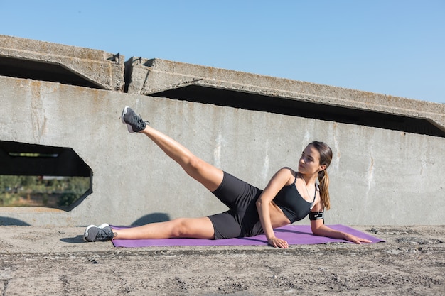 Una joven atlética delgada en ropa deportiva con estampados de piel de serpiente realiza una serie de ejercicios