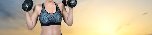 Una joven atlética delgada en ropa deportiva realiza una serie de ejercicios contra la puesta de sol junto al mar Realiza ejercicios con pesas Fitness y estilo de vida saludable