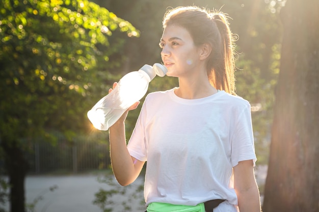 Una joven atlética descansa después de correr corredores cansados al atardecer en el parque