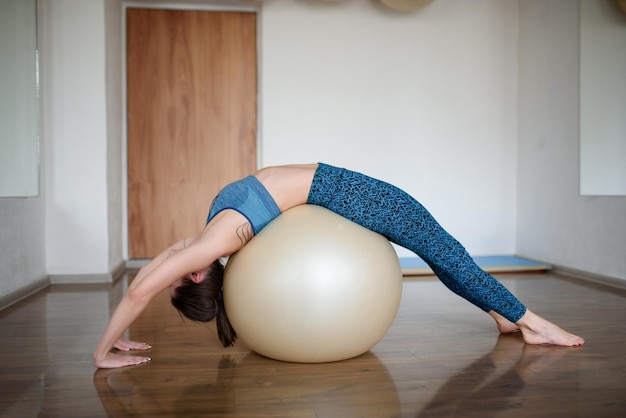 Una joven atlética entrena sus abdominales en una pelota de fitness en el gimnasio.