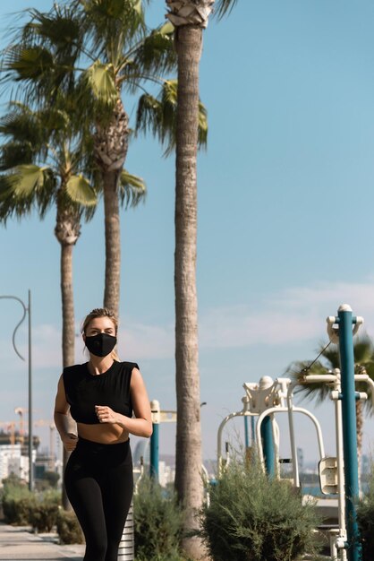 Joven atlética con mascarilla se está ejecutando durante su entrenamiento de jogging de verano