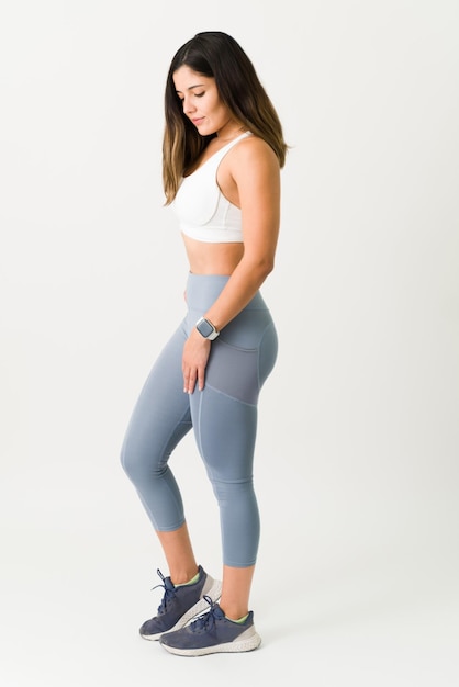 Foto joven atlética con ropa deportiva y a punto de hacer ejercicio. una mujer caucásica en forma lista para comenzar a hacer ejercicio sobre un fondo blanco