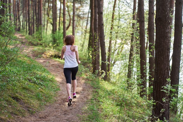 Joven atlética en zapatillas de color rosa en el bosque de la primavera