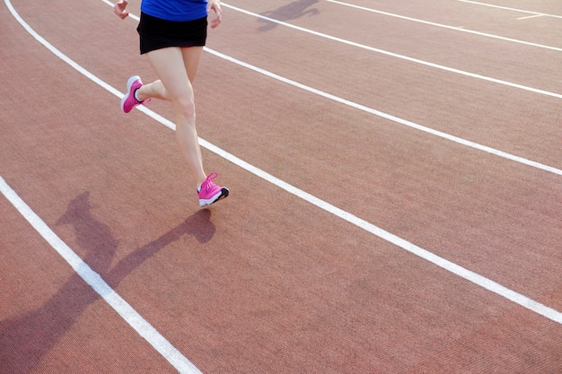 Joven atlética en zapatillas de color rosa en el estadio de atletismo