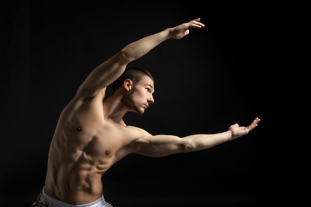 Joven atlético bailando contemporáneo sobre fondo negro