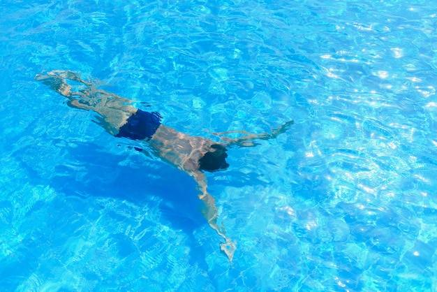 Joven atlético de buceo en la piscina