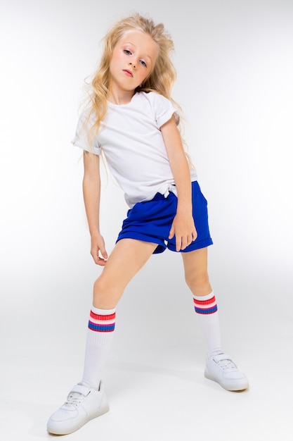 Joven atlético europeo encantador niño rubio en ropa deportiva con las manos posando en una pared blanca