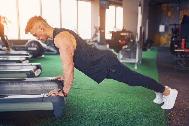 Joven atlético haciendo flexiones en el gimnasio