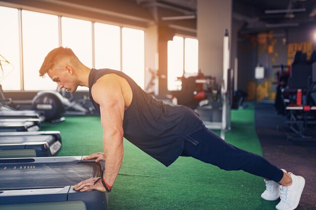 Joven atlético haciendo flexiones en el gimnasio