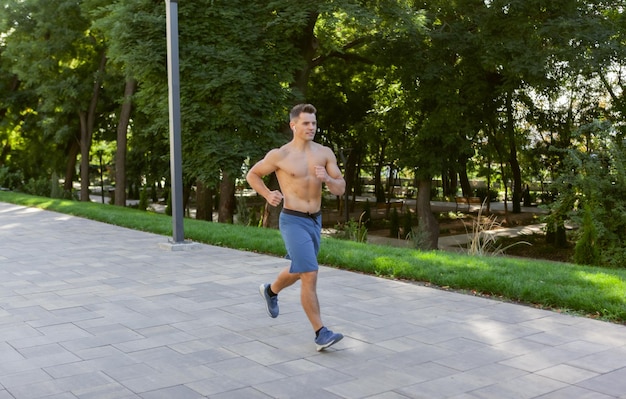 Joven atlético haciendo jogging al aire libre. Entrenamiento cardiovascular, estilo de vida saludable