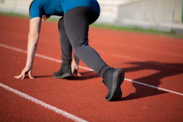 Joven atlético listo para correr en la pista de atletismo roja. Vista trasera. Fotografía de cerca