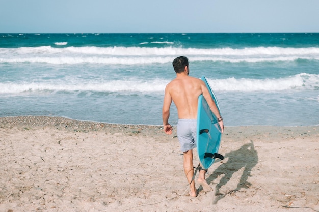 Joven atlético surfeando en la playa