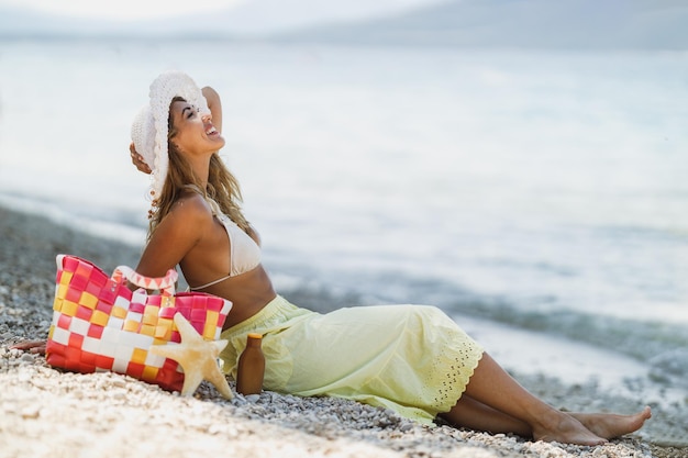Una joven atractiva en bikini relajándose en la playa. Está sentada y disfrutando del día de verano.