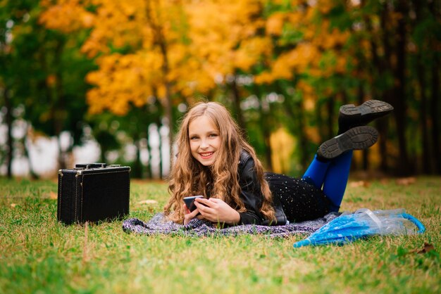 Joven atractiva chica sonriente bajo el paraguas en un bosque de otoño