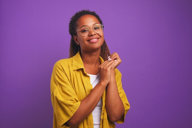 Joven atractiva mujer afroamericana se ve linda en la cámara y sonríe tímidamente