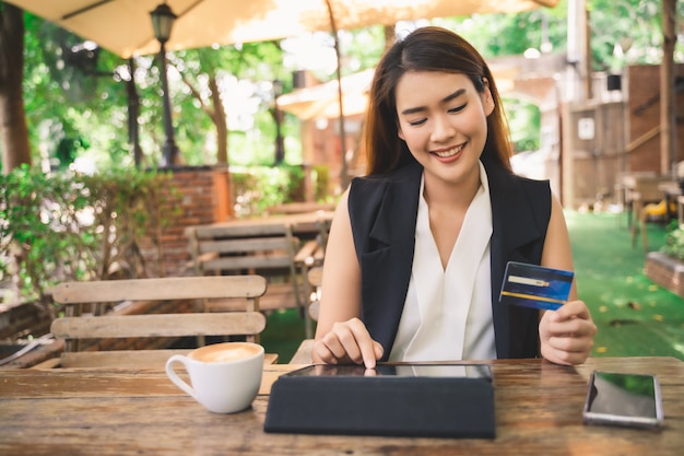 Foto joven atractiva mujer asiática feliz está usando tableta o teléfono inteligente