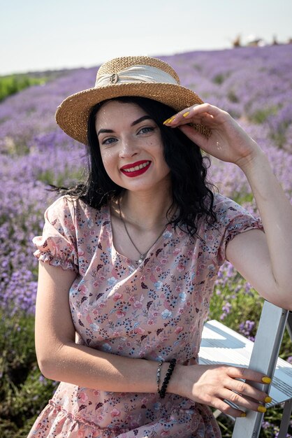 Joven atractiva mujer brunnete con sombrero rodeada de flores de lavanda