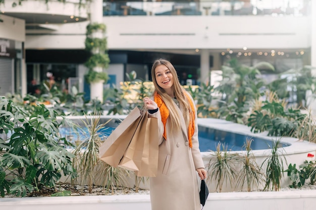 Joven atractiva mujer de ciudad fashionista con muchas bolsas en la mano va de compras