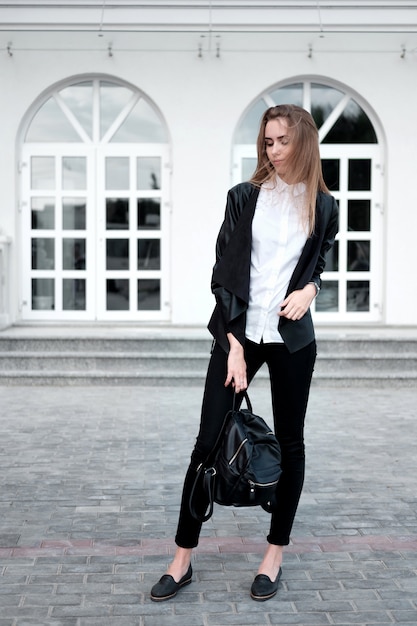 Joven atractiva mujer elegante en camisa blanca y pantalón negro