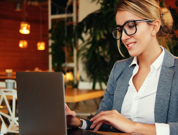 Una joven y atractiva mujer de negocios sentada en un café con una lapto