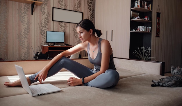 Joven atractiva mujer sonriente practicando yoga sentada en el ejercicio Half Lotus