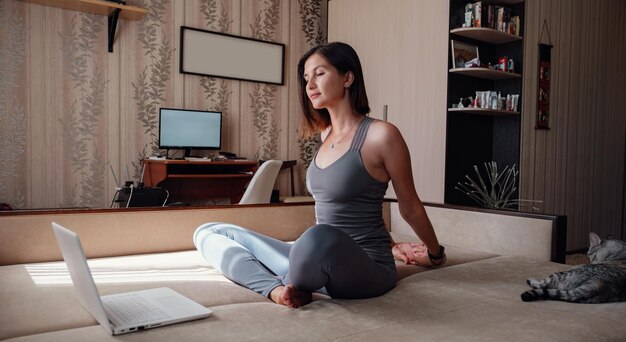 Joven atractiva mujer sonriente practicando yoga sentada en el ejercicio Half Lotus