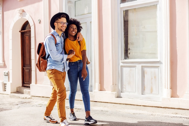 Joven atractiva pareja multirracial enamorada caminando al aire libre y disfrutando de un hermoso día soleado.