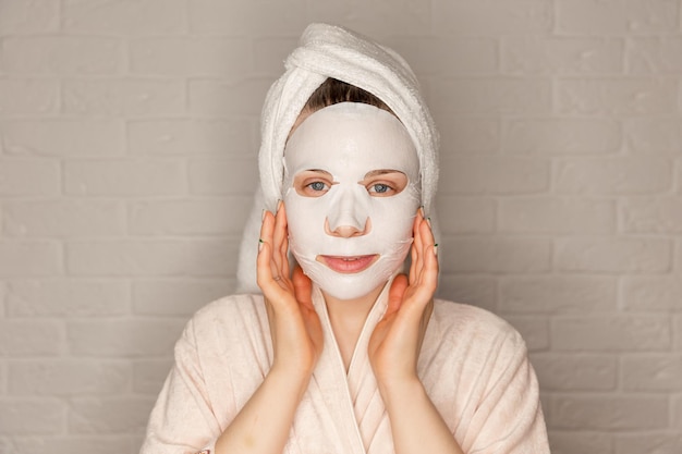 Una joven atractiva que aplica una máscara facial de algodón.