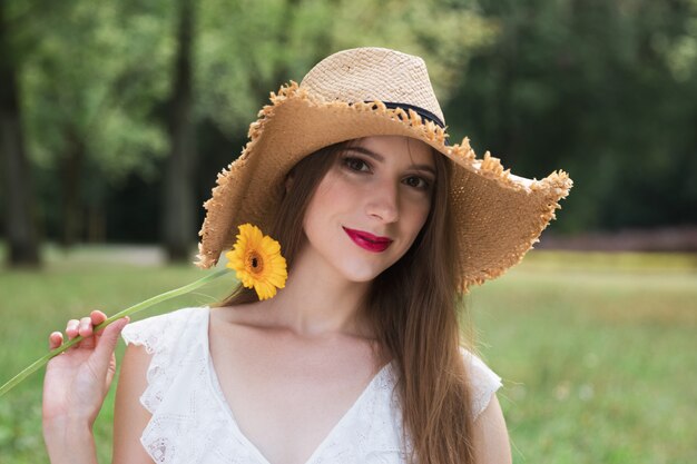 Joven atractiva tiene una flor silvestre de verano.