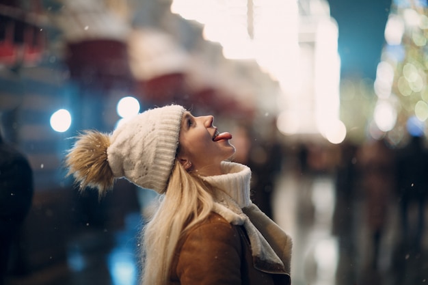 Joven atrapa los copos de nieve con la lengua boca