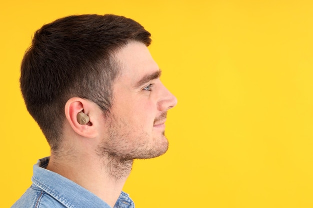 Foto joven con audífono sobre fondo amarillo