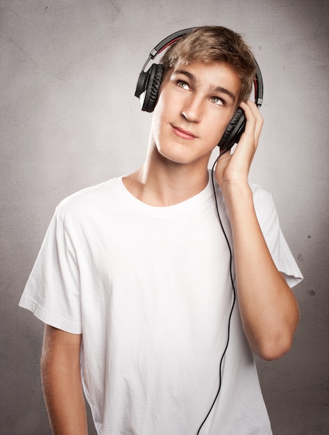 Joven con auriculares escuchando música en fondo gris