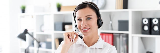 Una joven en auriculares con micrófono está en una oficina brillante.