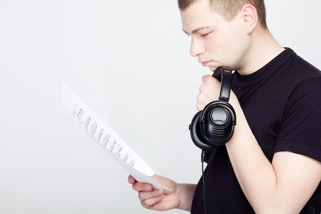 Joven con auriculares mira las notas musicales