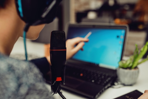 Un joven con auriculares modernos estudia desde casa usando una computadora portátil