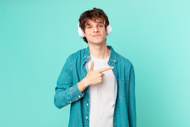 joven con auriculares sonriendo alegremente, sintiéndose feliz y apuntando hacia un lado