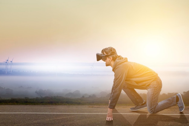 Joven en auriculares VR en posición de inicio listo en una carretera. Técnica mixta