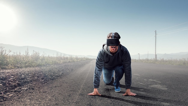 Foto joven en auriculares vr en posición de inicio listo en una carretera. técnica mixta