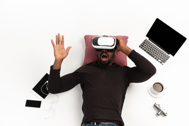 Joven con auriculares vr rodeado de gadgets aislados