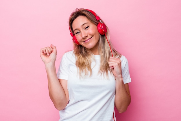 Joven australiana escuchando música aislada sobre fondo rosa