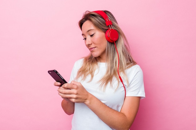 Joven australiana escuchando música aislada sobre fondo rosa