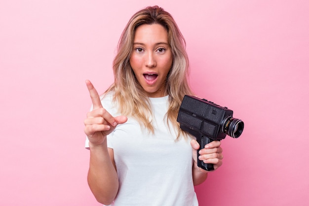 Joven australiana filmando con una cámara de video vintage aislada teniendo una idea, concepto de inspiración.