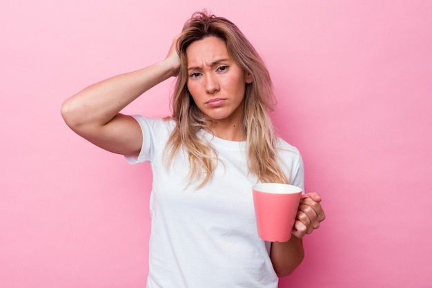 Joven australiana sosteniendo una taza rosa aislada sobre fondo rosa conmocionada, ha recordado una reunión importante.