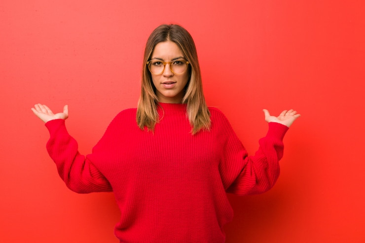 Foto joven auténtica mujer carismática de personas reales contra una pared hace escala con los brazos, se siente feliz y confiada.