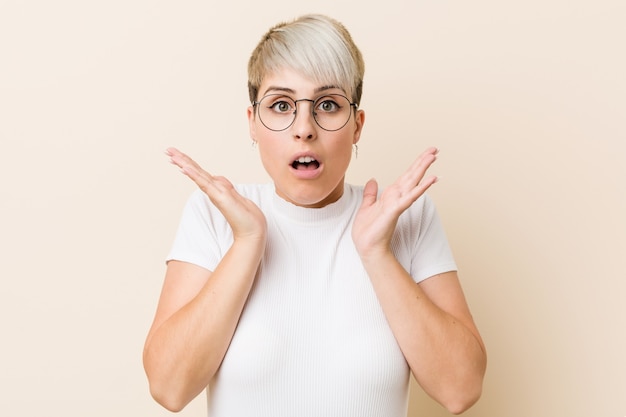 Joven auténtica mujer natural con una camisa blanca sorprendida y conmocionada.